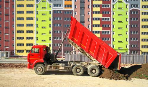 Multistorey building apartment house and dump truck unload soil.